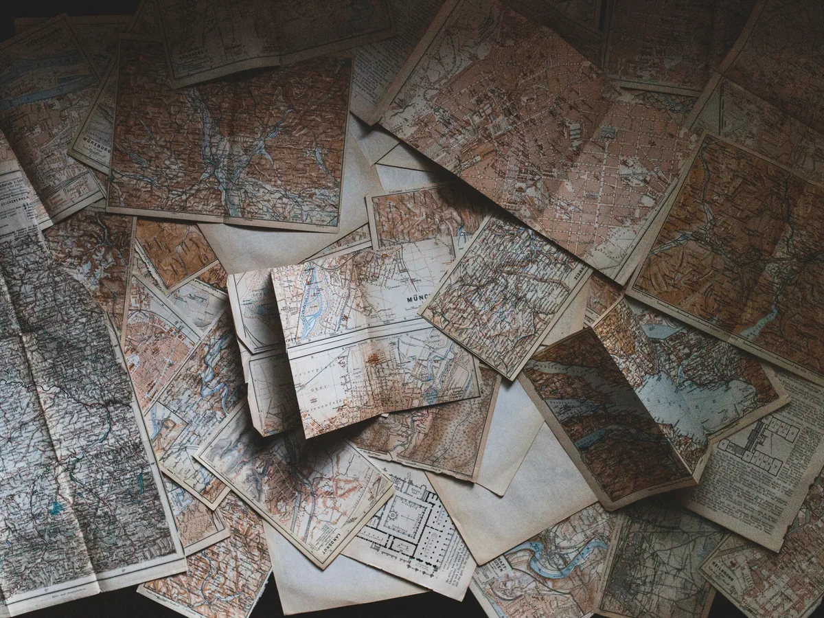 Folded maps and travel guides spread out on a wooden floor