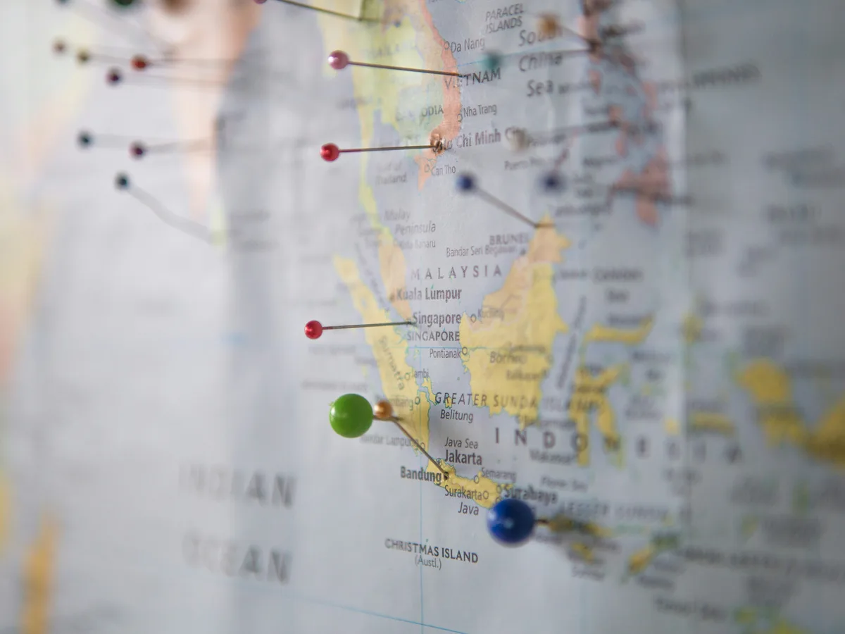 A world map marked with pins, passport, and travel planning notes